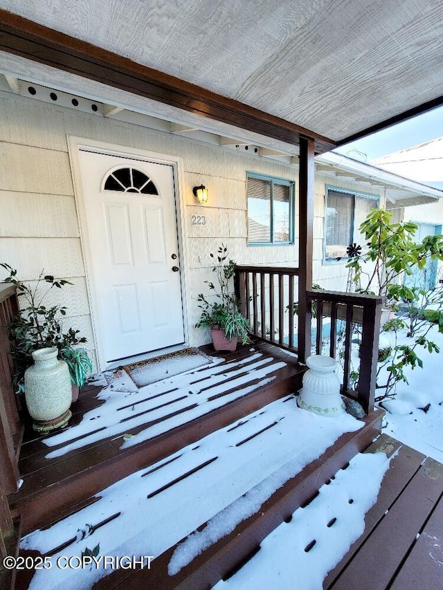 snow covered property entrance featuring covered porch