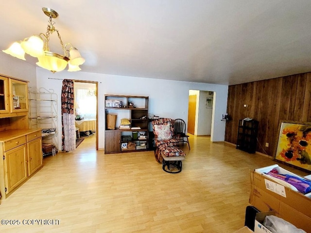 living room with wooden walls, a chandelier, and light hardwood / wood-style flooring