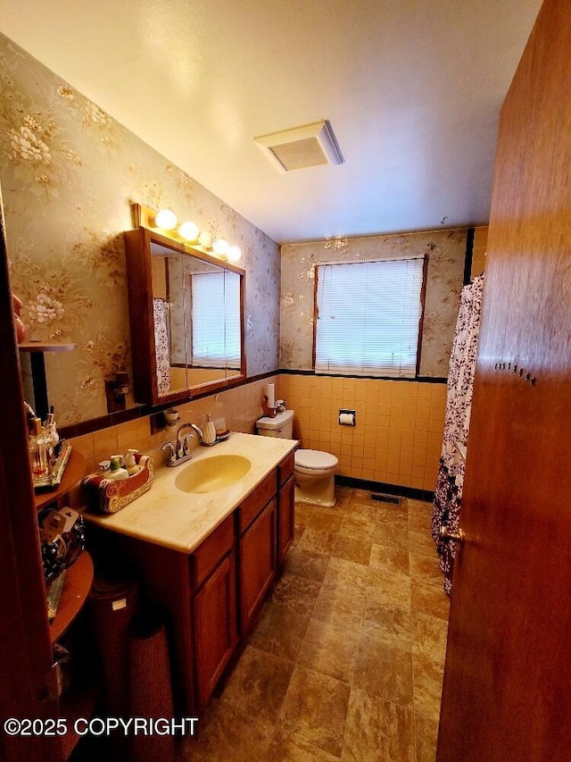 bathroom featuring tile walls, vanity, and toilet