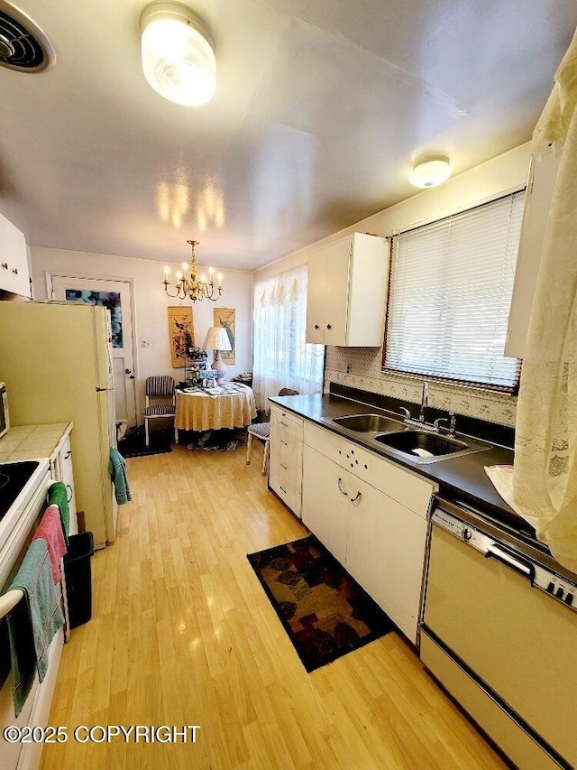 kitchen with dishwashing machine, sink, light hardwood / wood-style floors, and white cabinets