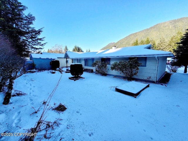 snow covered house featuring a mountain view