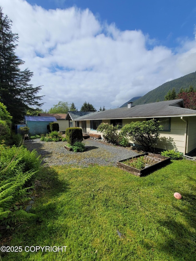 223 Lakeview Dr, Sitka, AK 99835 - back of house featuring a lawn and a vegetable garden