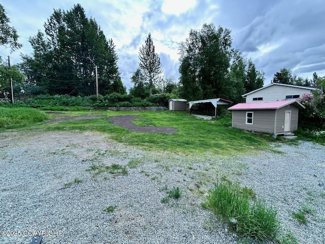 12421 Silver Spruce Dr, Anchorage, AK 99516 - view of yard featuring a carport, a storage unit, and driveway