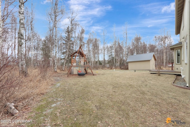 view of yard featuring a playground, an outdoor structure, fence, and a shed