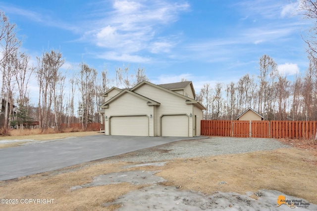 view of home's exterior with driveway, a garage, and fence