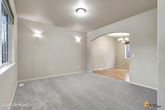 carpeted spare room with arched walkways and baseboards