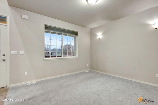 carpeted spare room with visible vents and baseboards