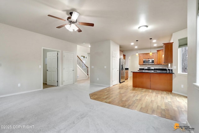 kitchen with light carpet, dark countertops, open floor plan, a peninsula, and stainless steel appliances