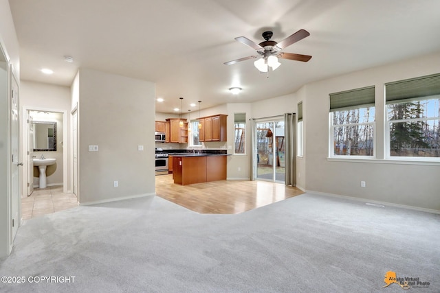 kitchen with recessed lighting, light colored carpet, open floor plan, appliances with stainless steel finishes, and dark countertops