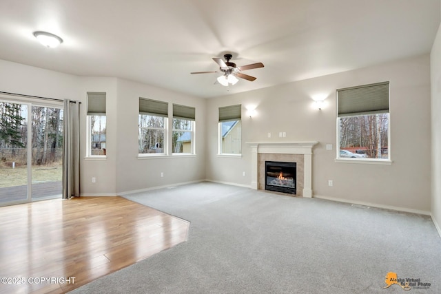 unfurnished living room featuring a healthy amount of sunlight, baseboards, a ceiling fan, and a tile fireplace