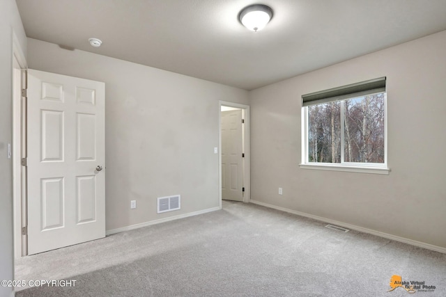 unfurnished bedroom with carpet floors, visible vents, and baseboards