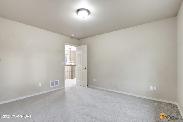 carpeted spare room featuring visible vents and baseboards