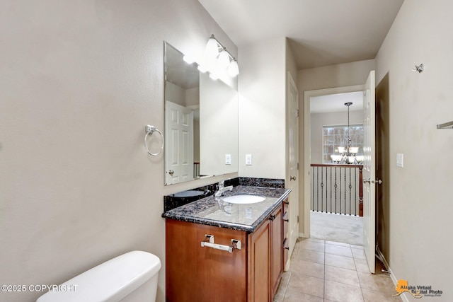 half bathroom with toilet, an inviting chandelier, tile patterned flooring, and vanity