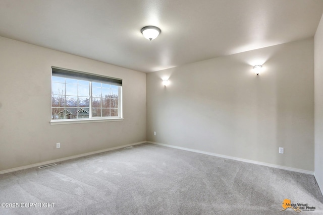 spare room featuring carpet, visible vents, and baseboards