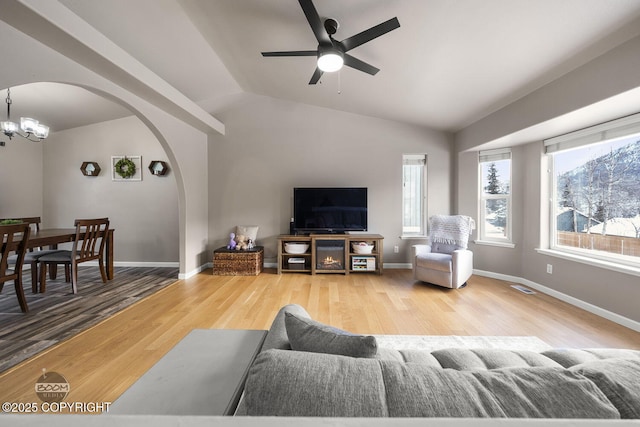 living room featuring hardwood / wood-style flooring, ceiling fan with notable chandelier, and vaulted ceiling