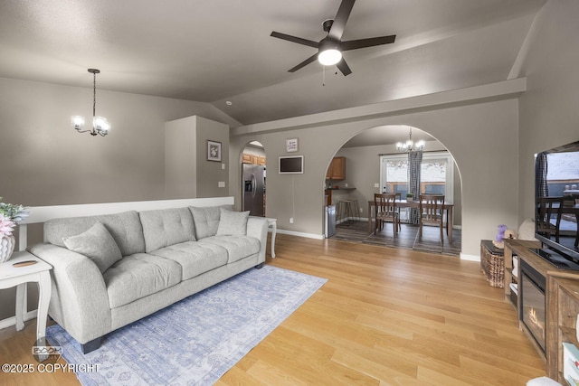 living room with hardwood / wood-style flooring, vaulted ceiling, and ceiling fan with notable chandelier