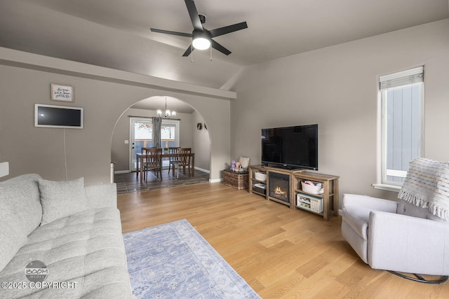 living room with wood-type flooring, vaulted ceiling, and ceiling fan with notable chandelier