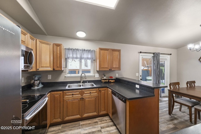 kitchen with an inviting chandelier, stainless steel appliances, kitchen peninsula, and sink