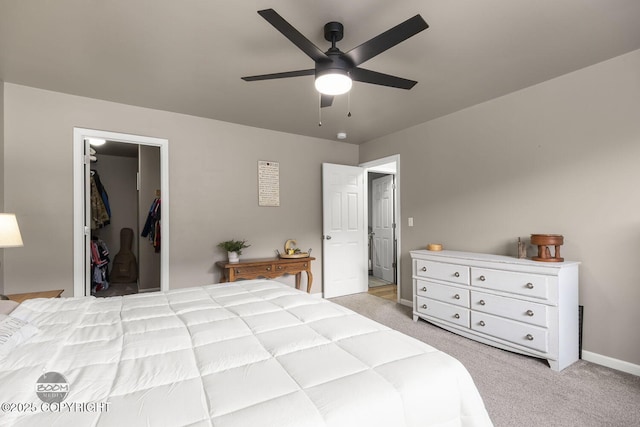 bedroom with a walk in closet, light colored carpet, and ceiling fan