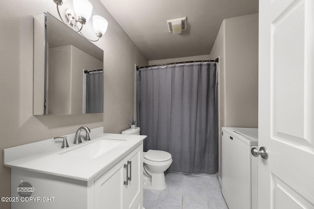 bathroom featuring tile patterned flooring, vanity, washer / clothes dryer, and toilet