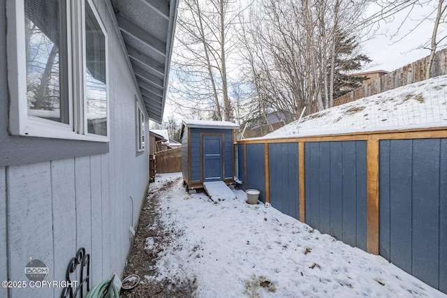 yard layered in snow featuring a storage shed