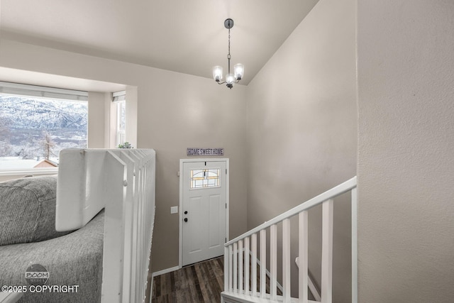 foyer with lofted ceiling, dark wood-type flooring, a wealth of natural light, and a chandelier