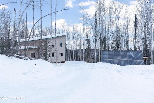 snow covered rear of property with solar panels