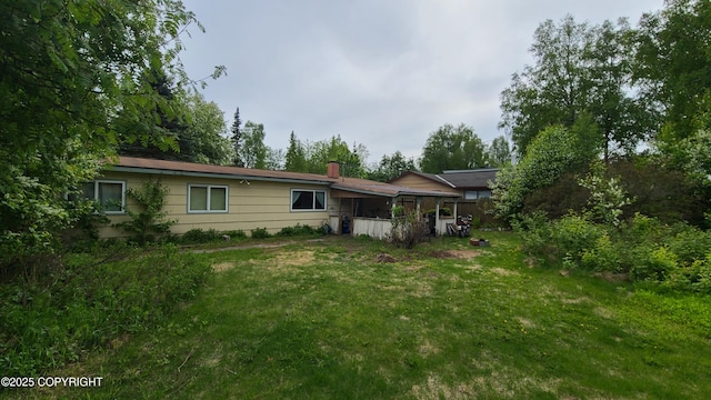 2911 W 34th Ave, Anchorage, AK 99517 - back of property with a chimney, a yard, and a sunroom