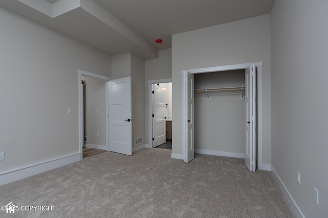 unfurnished bedroom featuring light carpet, visible vents, baseboards, and a closet