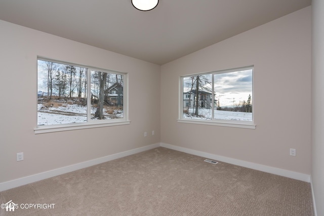 unfurnished room with lofted ceiling, visible vents, a wealth of natural light, and light colored carpet