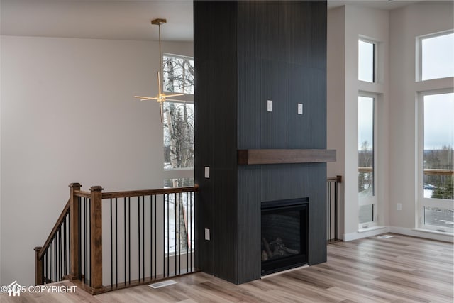 stairs with a high ceiling, visible vents, a fireplace, and wood finished floors