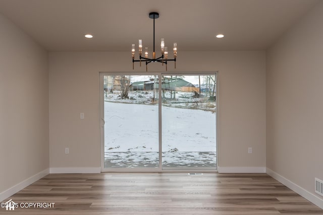 unfurnished dining area featuring a chandelier, recessed lighting, light wood finished floors, and baseboards