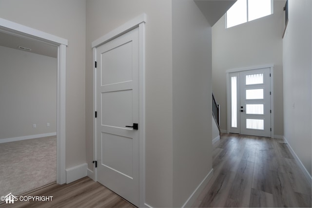 foyer entrance with light wood-type flooring, stairway, and baseboards