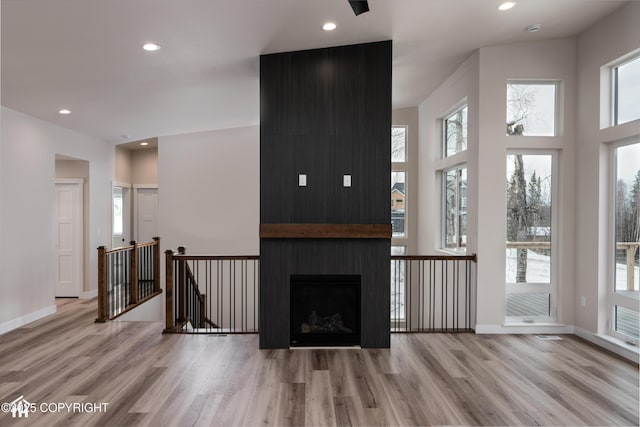 living room featuring light wood-type flooring, a fireplace, baseboards, and recessed lighting