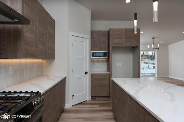 kitchen featuring light stone countertops, pendant lighting, and ventilation hood