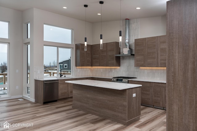 kitchen with appliances with stainless steel finishes, decorative light fixtures, a kitchen island, and decorative backsplash