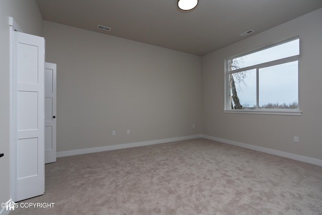 unfurnished room with baseboards, visible vents, and light colored carpet