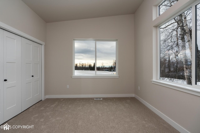 unfurnished bedroom featuring baseboards, a closet, visible vents, and light colored carpet