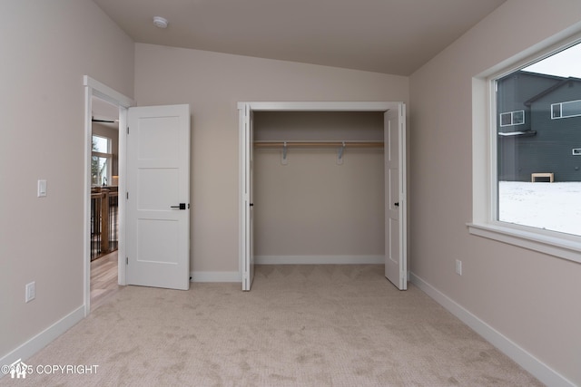 unfurnished bedroom with light carpet, baseboards, and multiple windows