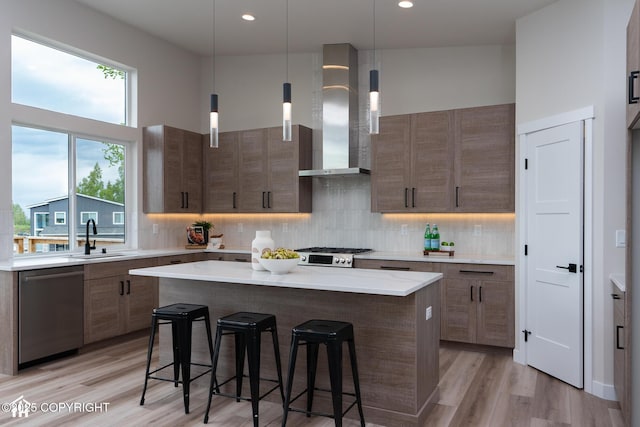 11093 Red Sky Cir, Anchorage, AK 99516 - kitchen featuring stainless steel dishwasher, a breakfast bar, wall chimney exhaust hood, decorative backsplash, and a center island
