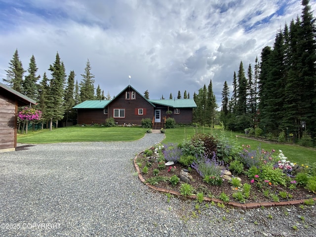 view of front of property featuring metal roof, a front lawn, and gravel driveway