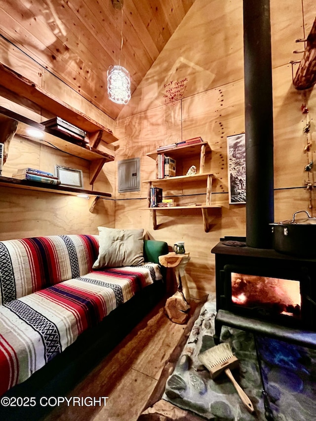 interior space featuring vaulted ceiling, a wood stove, wood ceiling, and wood walls