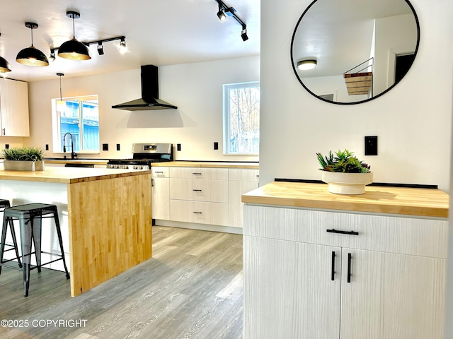 kitchen with light wood-type flooring, a breakfast bar, wood counters, and ventilation hood