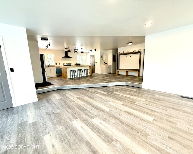 unfurnished living room with wood finished floors and visible vents