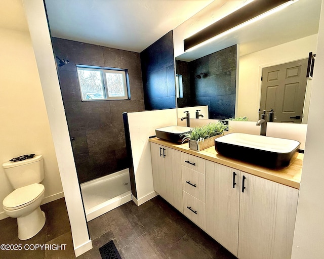 bathroom featuring toilet, a sink, and tiled shower