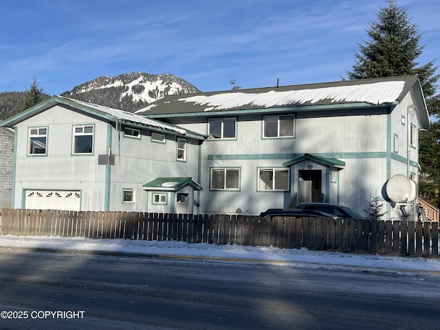 snow covered property with a garage and a mountain view