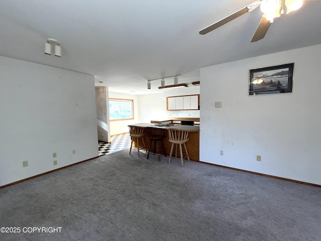 unfurnished living room with ceiling fan, rail lighting, and carpet