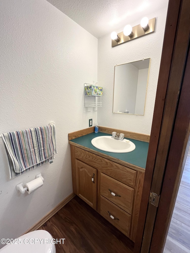 bathroom with hardwood / wood-style flooring, vanity, a textured ceiling, and toilet