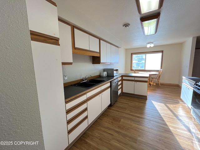 kitchen with sink, stainless steel dishwasher, white cabinets, and light wood-type flooring