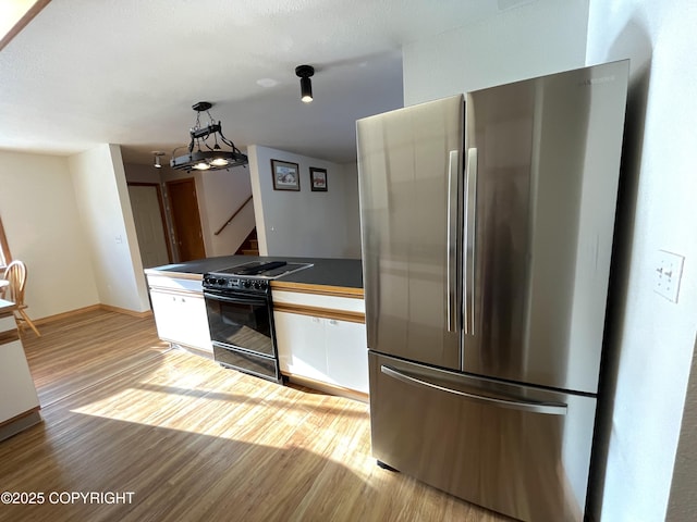 kitchen with white cabinetry, hanging light fixtures, stainless steel fridge, electric stove, and light hardwood / wood-style floors